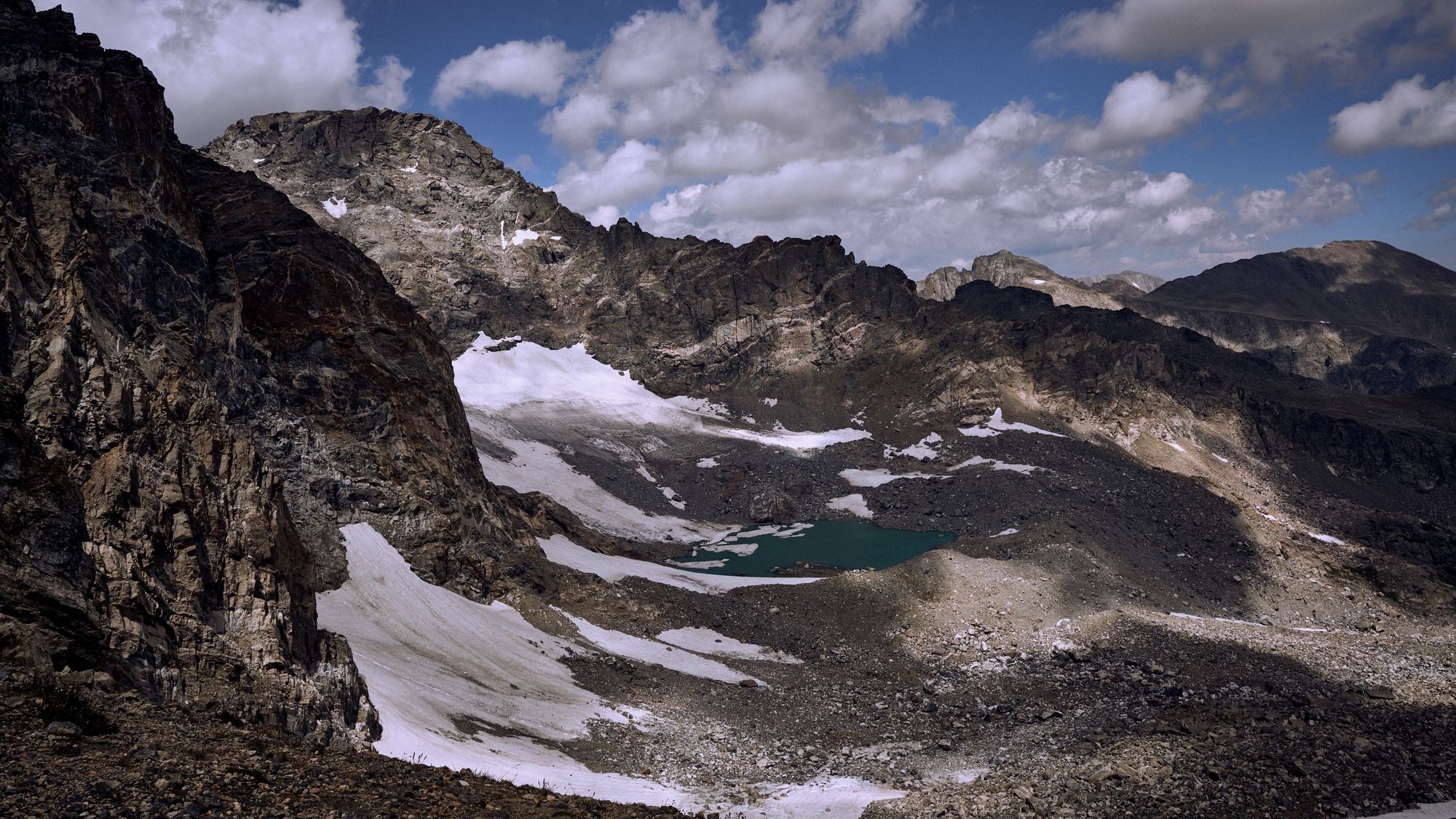 Photo of mountains, clouds, and a small lake. The North Arapaho peak taken from the South Arapaho peak.