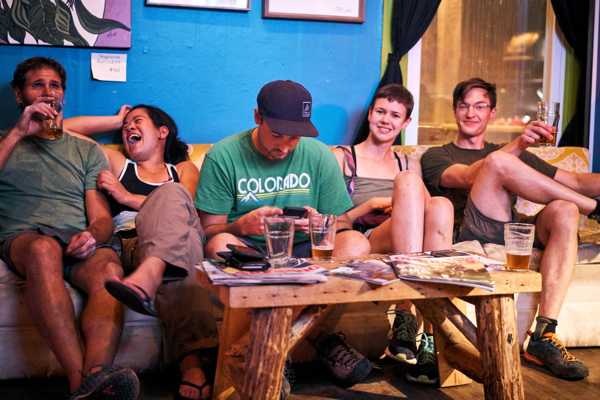 Group of people laughing and driking on a sofa at a restaurant.