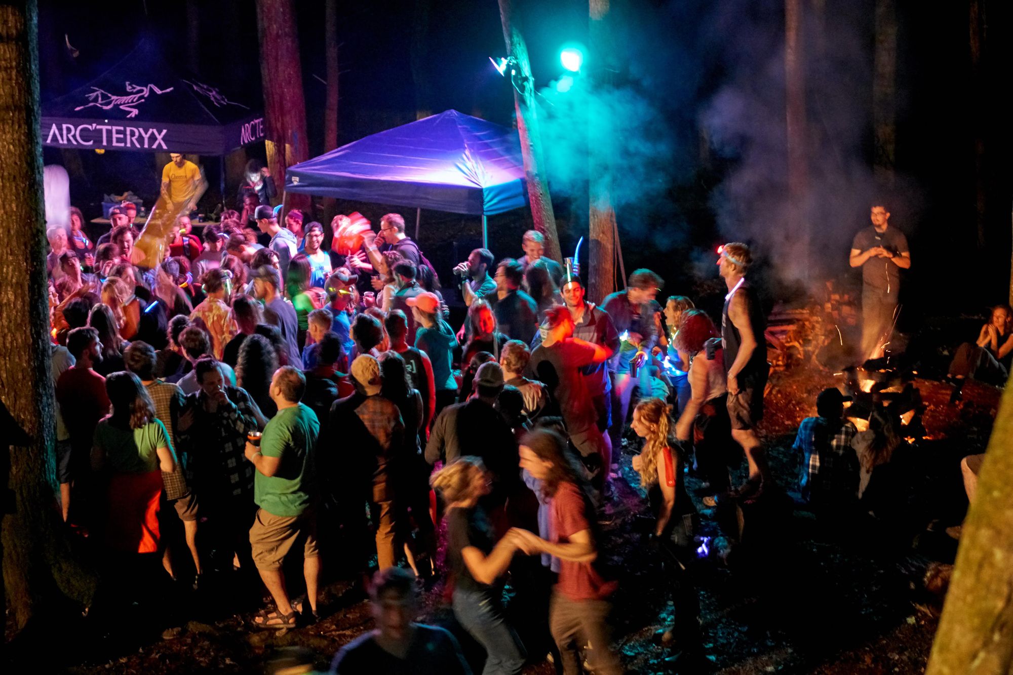 Party outside at night with smoke and colored lights.