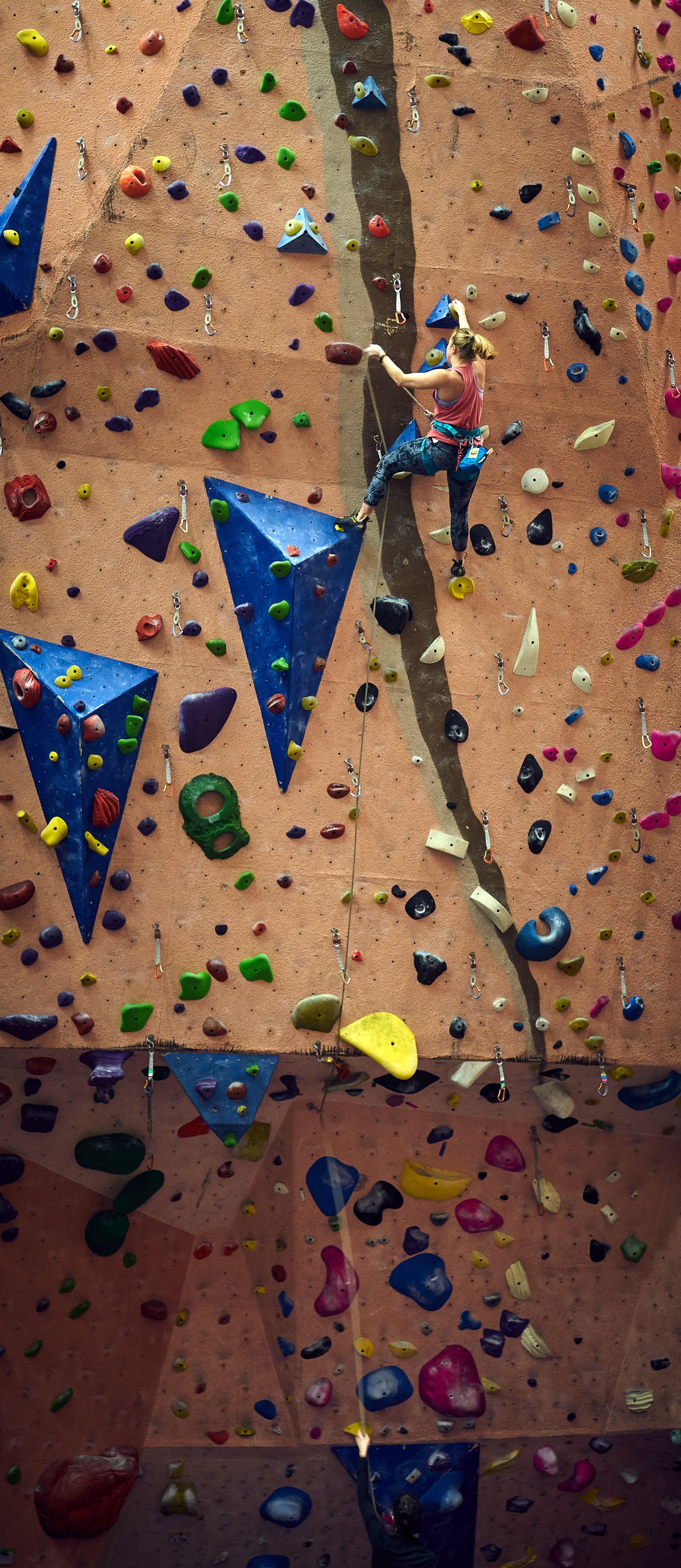 Woman climbing a steep indoor climb.