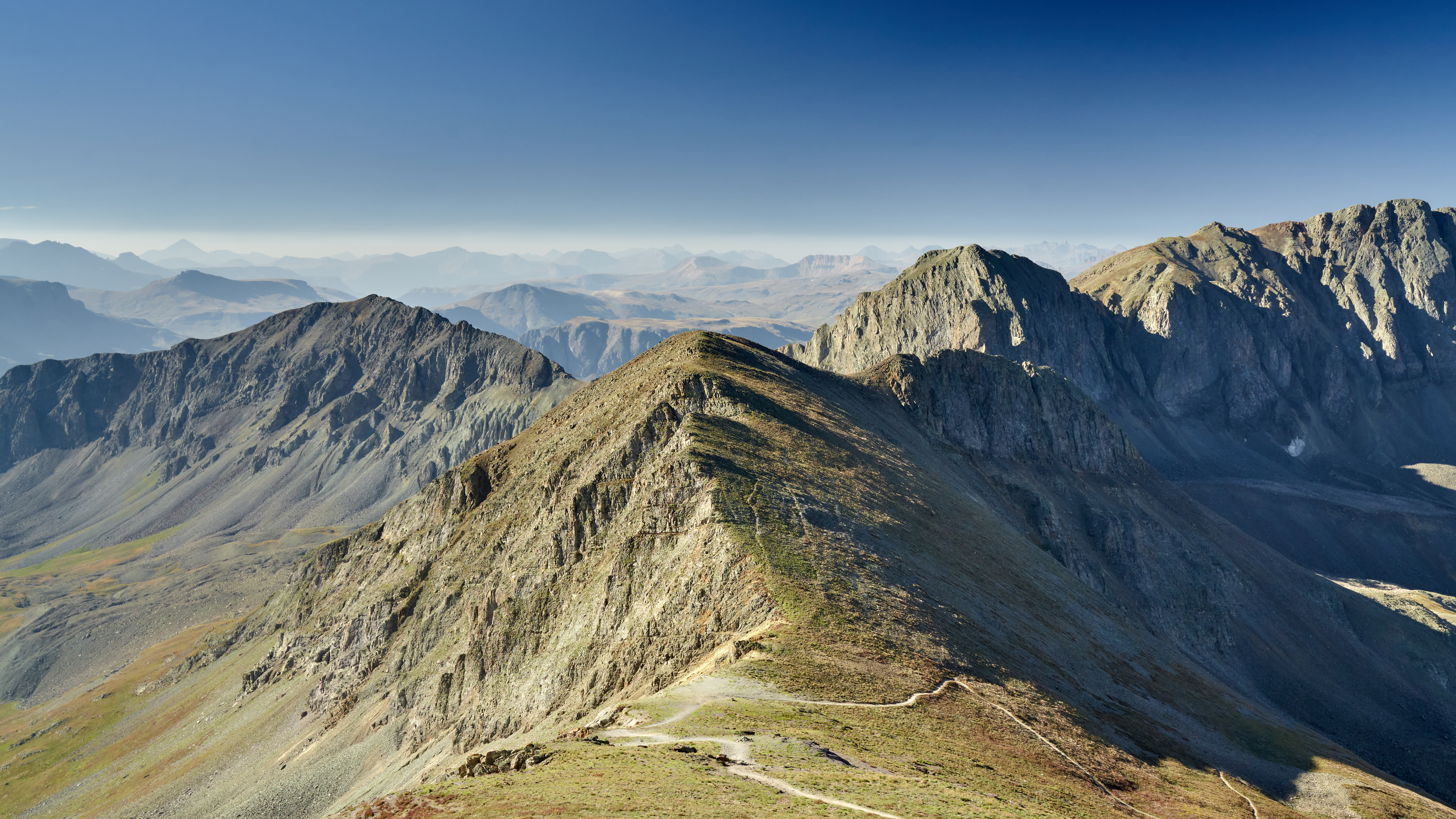 High up mountain peak looking far out into the landscape, with more mountains