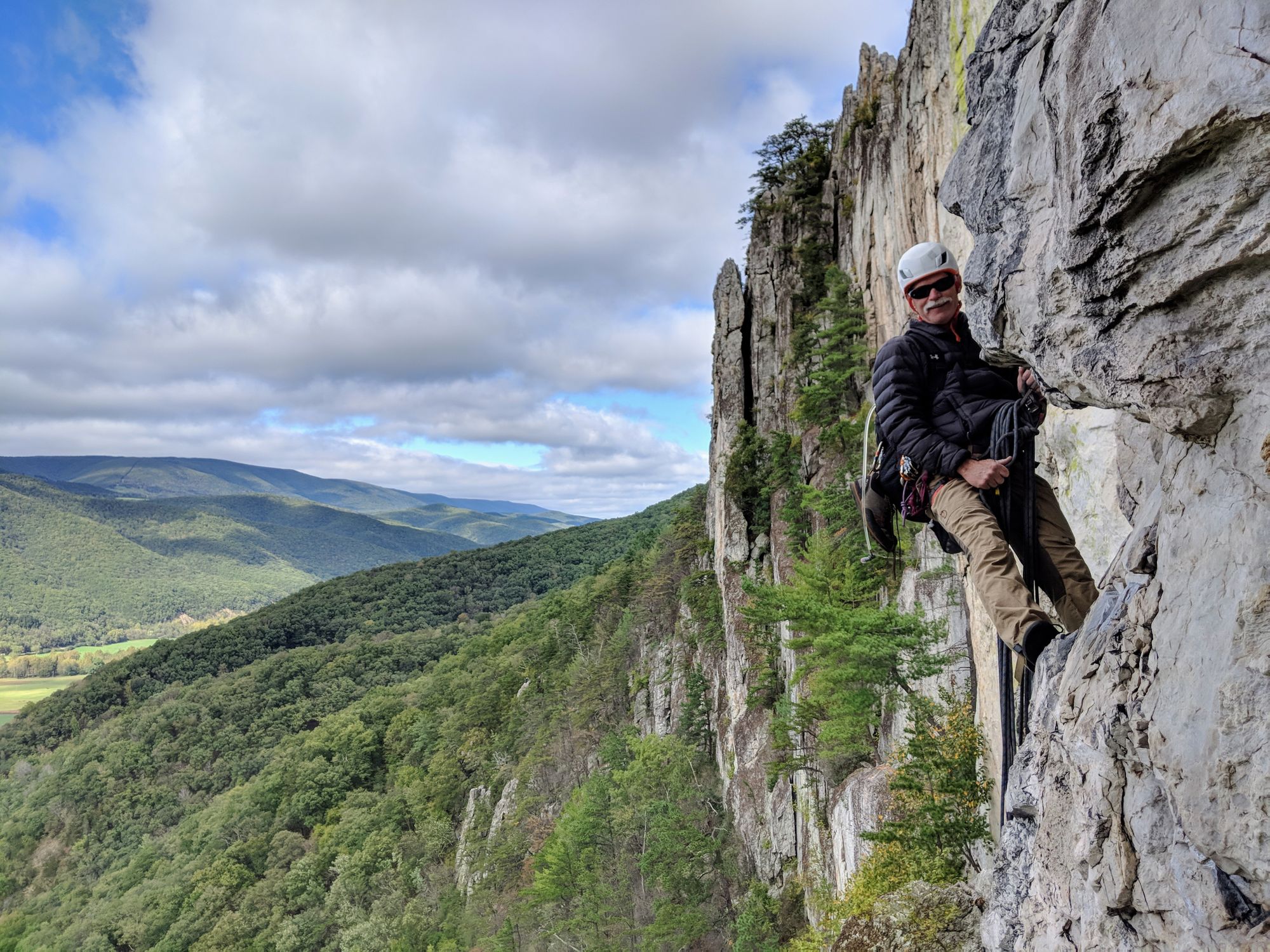 Man hanging high in the air on a rock climb.