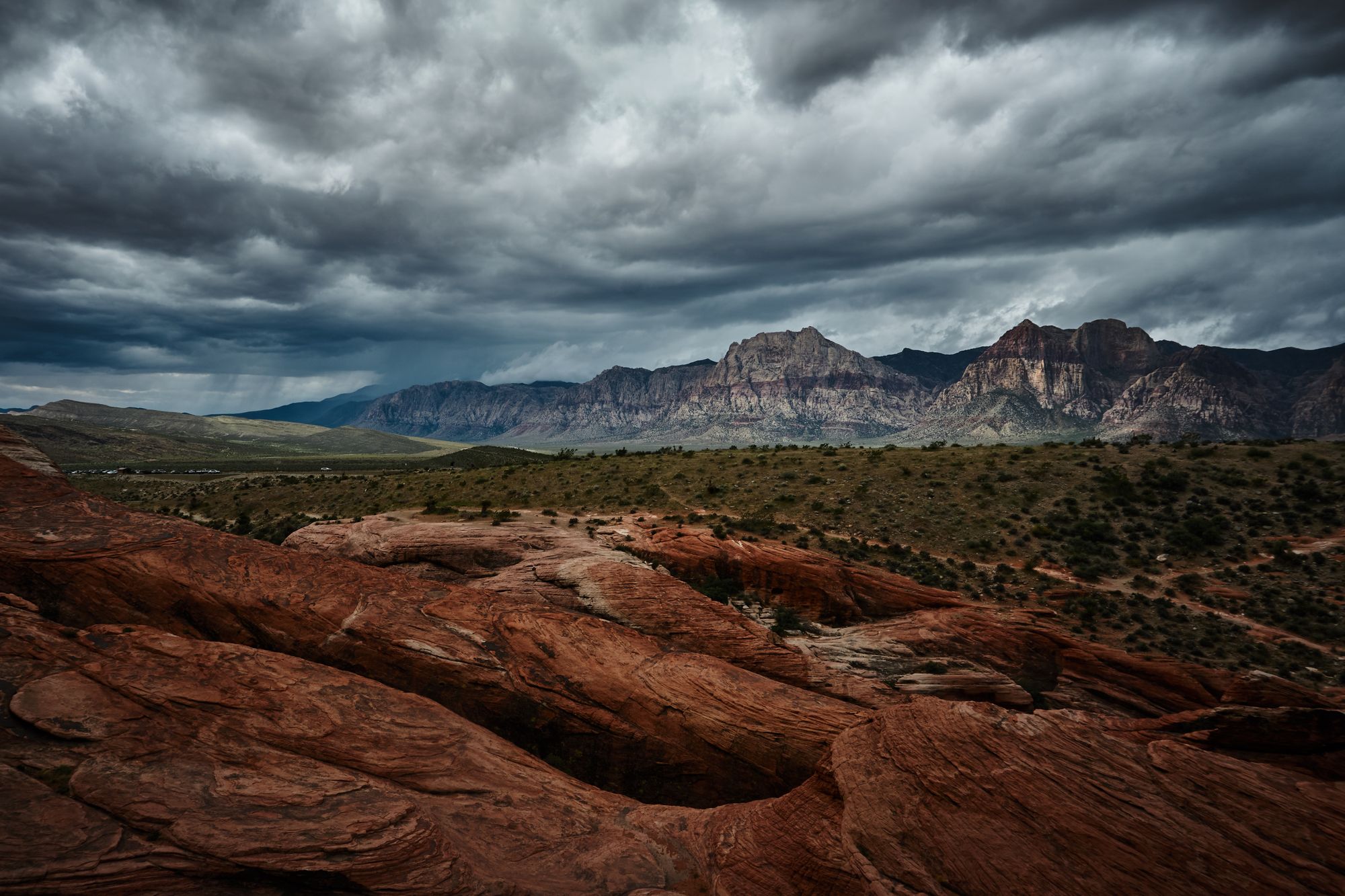 Dramatic storm clouds seen with red rocks canyons in the distance.