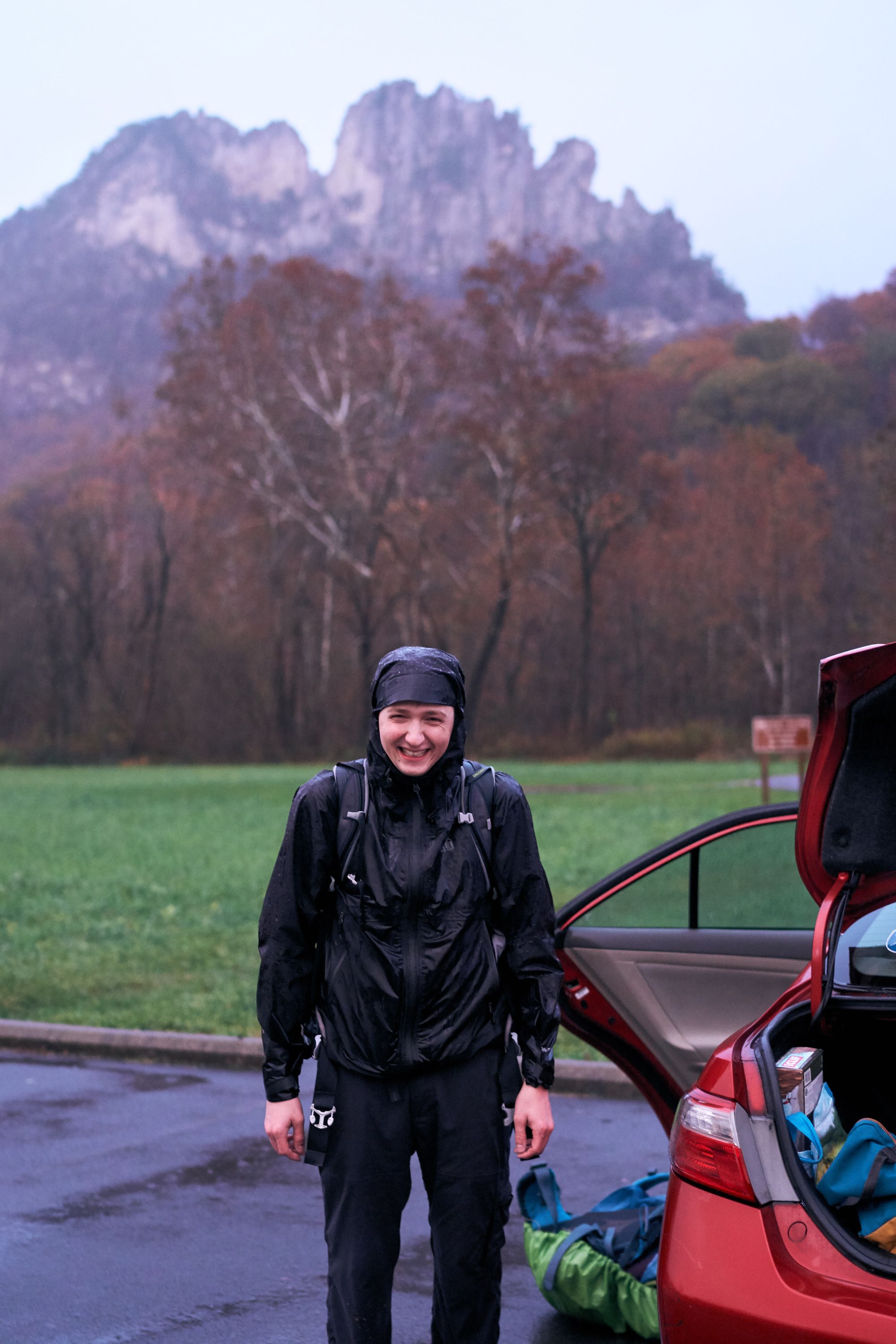 Steve in a rainjacket at the parking lot, with the seneca rock structure a mile behind him.