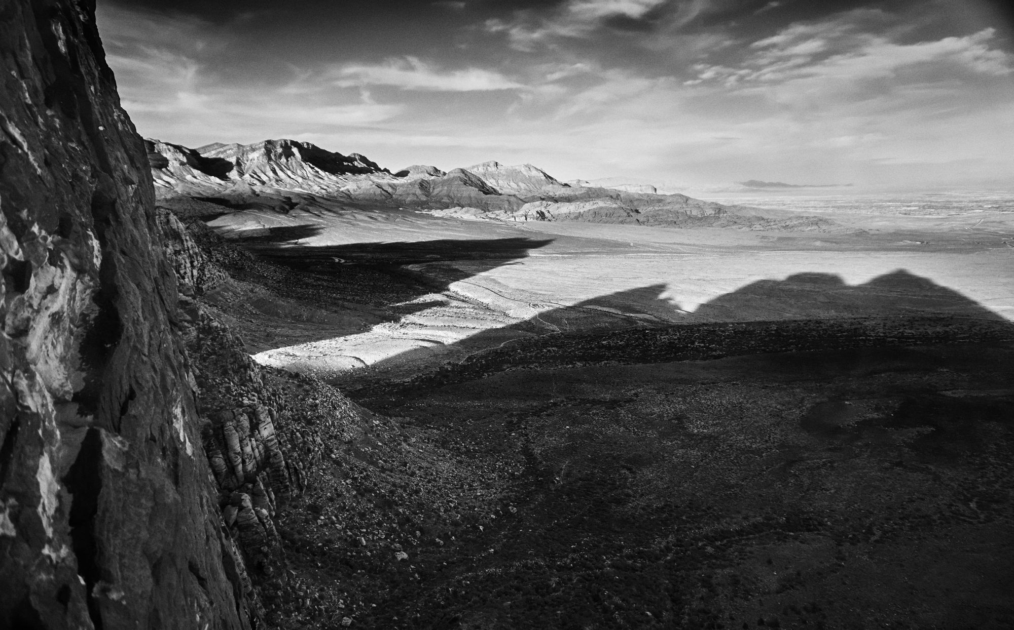 Black and white silhouette of mountains casting a shadow across the landscape.