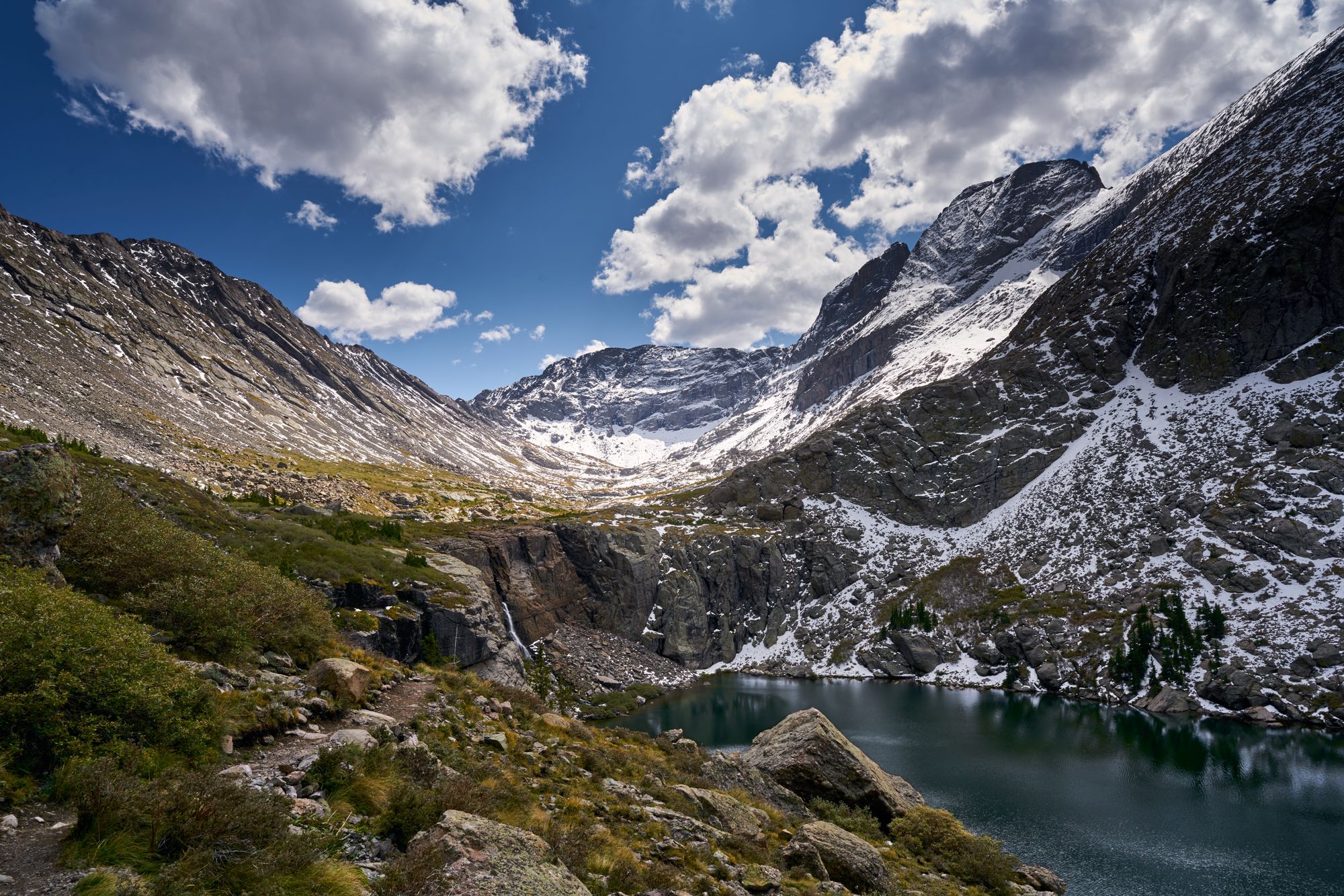 Photo of mountains, clouds, and a small lake. The North Arapaho peak taken from the South Arapaho peak.